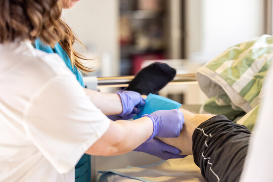 Nurse applying absorbent dressing to patient leg wound during clinical wound care treatment in hospital