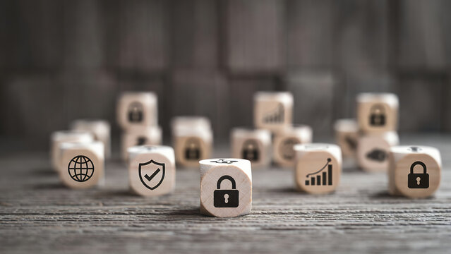 Various wooden cubes displaying business, security, and growth icons are scattered across a wooden surface.