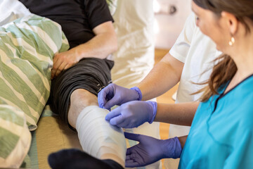 Obraz premium Nurse performing wound dressing change on patient leg during clinical nursing care in hospital ward