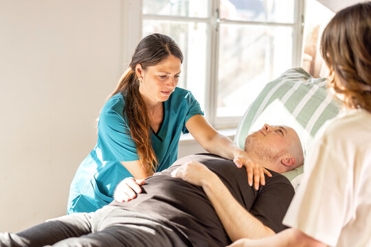 Nurses repositioning patient in hospital bed for pressure ulcer prevention and safe nursing care