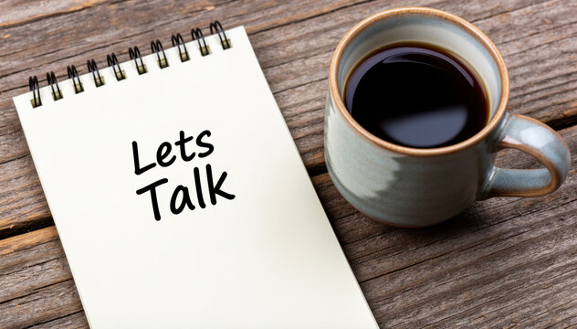 Cozy Conversation: A notebook with the words Lets Talk sits beside a warm cup of coffee on a rustic wooden table, inviting to intimate discussion. 