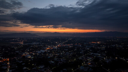 Naklejka premium Cityscape lights illuminating at sunset with mountains