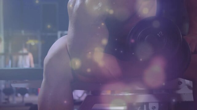 Male athlete grabbing dumbbell at gym, lifting one-arm rowing, purple bokeh showing back strength