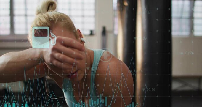 Woman pausing during fitness, wiping sweat, recovering between sets while teal data bars floating