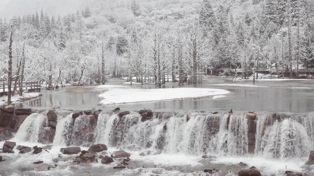 Snowscape of Changping Valley, Siguniang Mountain in Sichuan, China. Snowflakes falling, white snow capped forest, dead tree beach waterfall, 4k slow motion footage b roll shot travel concept