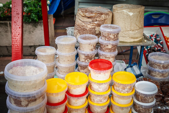 Plastic tubs and large blocks of halva for sale at an outdoor market stall in Serbia. Traditional sesame based sweet with marbled texture, shown as bulk confection and local dessert for shoppers.