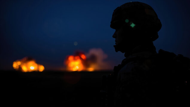 Silhouette of soldier at night with distant explosions creating dramatic orange glow