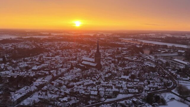 Aerial shot of Doesburg in the Netherlands with fresh snow and a dramatic sunrise sky above the town.