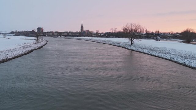Drone footage of a snowy Doesburg during a vibrant sunrise, highlighting historic architecture and winter atmosphere.