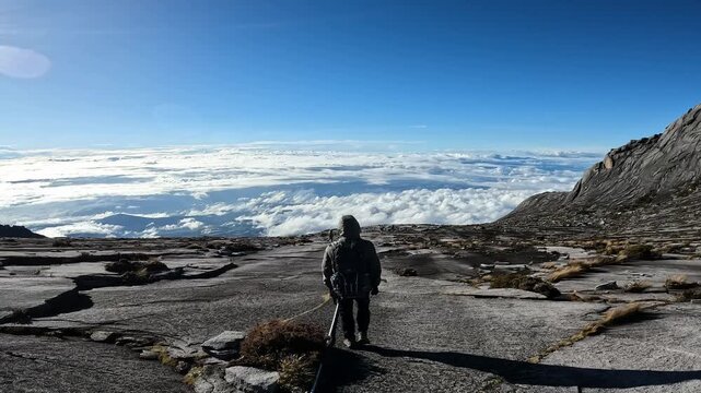 Rear view of tourist walking on rock plateau on Mt.Kinabalu. Mt.Kinabalu is the highest mountain in Borneo and Malaysia.