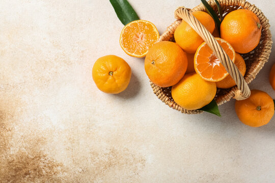 Wicker basket with sweet mandarins on white background