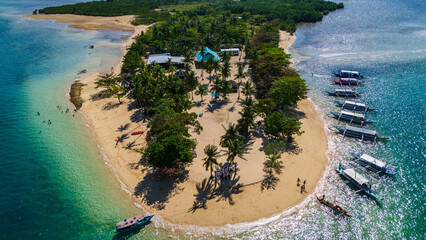 aerial drone above Cowrie Island in the Philippines, Palawan island , capturing the vibrant turquoise waters and pristine white sand with boat anchored along the palm-fringed shore © Michele