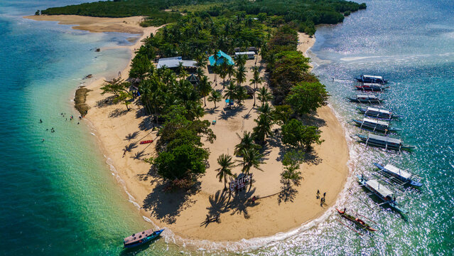aerial drone above Cowrie Island in the Philippines, Palawan island , capturing the vibrant turquoise waters and pristine white sand with boat anchored along the palm-fringed shore