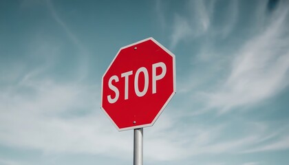 Bright Red Octagonal Stop Sign with White Text Against a Clear Blue Sky Symbolizing Caution.