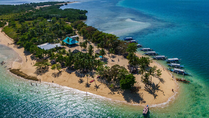 aerial drone above Cowrie Island in the Philippines, Palawan island , capturing the vibrant turquoise waters and pristine white sand with boat anchored along the palm-fringed shore © Michele