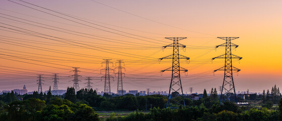 High voltage electricity pylons and transmission lines at sunset. Power grid and energy infrastructure industry concept.