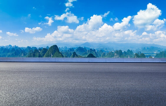 Empty asphalt highway and karst mountain landscape under a blue sky in Guilin, China.