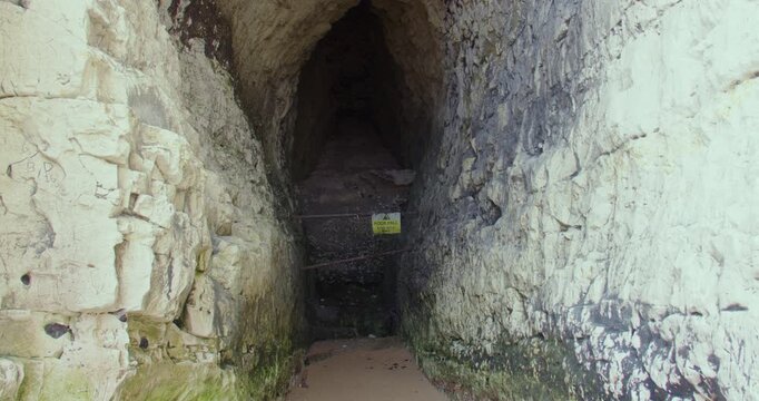 Slow zoom in onto a cave in chalk cliffs at Kingsgate beach bay. At low tide.