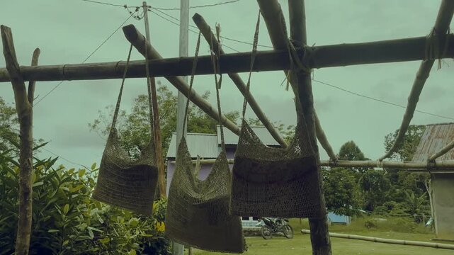 Traditional Papuan Noken Bags Hanging on Bamboo Rack for Drying in Village