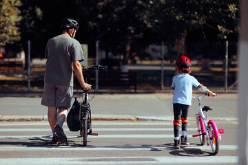 Naklejka premium Father and Daughter Safely Crossing the Street with Bicycles. Active family enjoying outdoors activity together 