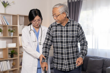 Obraz premium Senior man practicing walking with cane assisted by female healthcare professional during home rehabilitation session in modern living room, elderly care, physical therapy and recovery.