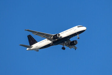 Obraz premium White and dark blue passenger jet airplane landing on a sunny winter day at Iona Beach Regional Park in Vancouver Canada