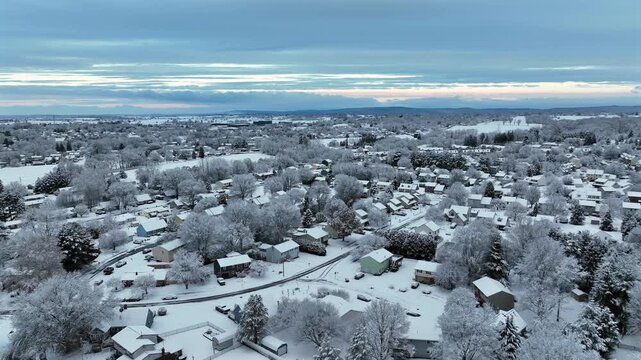 Peaceful and quiet American suburban neighborhood covered in fresh snow with icy trees and houses during calm winter morning. Aerial wide shot. Christmas season in Pennsylvania state.