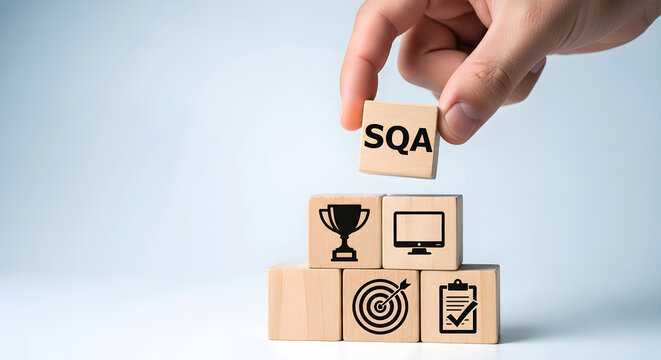 Hand placing SQA block on top of stacked wooden blocks with business icons