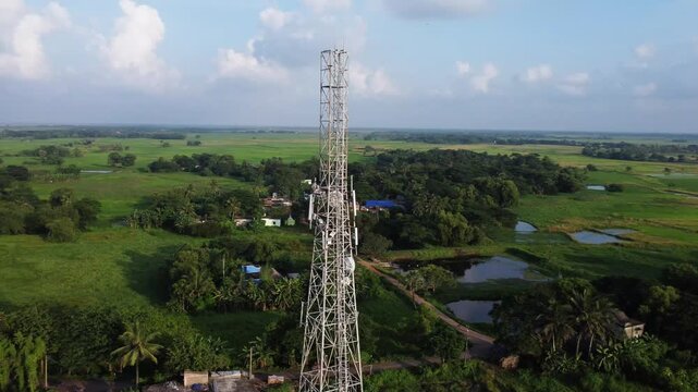 Aerial View of Telecommunication Tower in Vast Rural Green Landscape. Indian Telecommunication Tower  in Odisha. Signal Tower and Rural Housing. Network Communication Tower in Scenic Countryside.