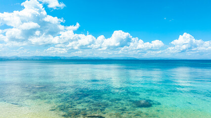 Fototapeta premium Tropical Nature clear sky and summer sea water under a clear blue sky with beautiful clouds and bright sunlight. Perfect for summer vacation and travel background 