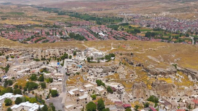 Urgup, Nevsehir, Turkey. Ancient city carved into rocky cliffs contrasted with modern new town development in Cappadocia.. Aerial View, MasterShots, Spiral forward