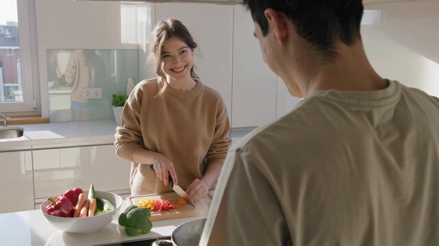 Young couple joyfully preparing a plant-based meal together in a bright, modern kitchen