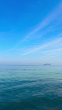 Vertical video of nature tropical and clear sky and summer sea water under a clear blue sky with beautiful clouds and bright sunlight. Perfect for summer vacation and travel background