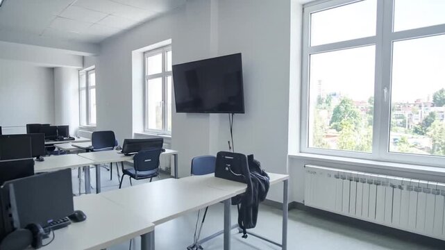 Empty modern computer lab classroom with projector screen and multiple workstations ready for students or training session during daytime
