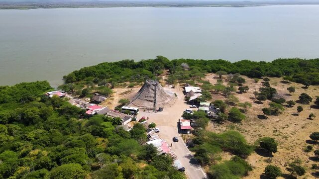 Aerial capture showing Totumo Volcano with lush green surroundings and a visible pathway. Nearby structures add to the scenic view.