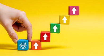 Hand touching blue cube with target symbol next to ascending colorful cubes with arrows on yellow