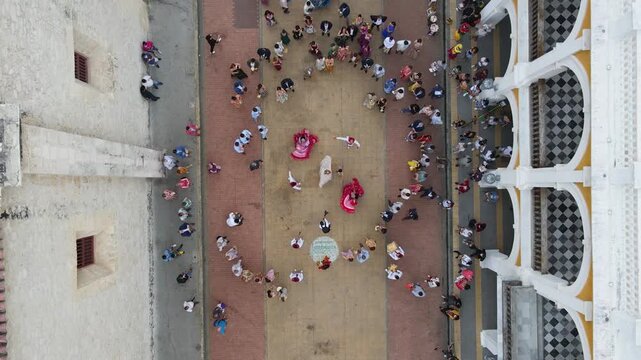 Aerial view of a vibrant dance performance with pink costumes in a lively plaza surrounded by a crowd in Cartagena