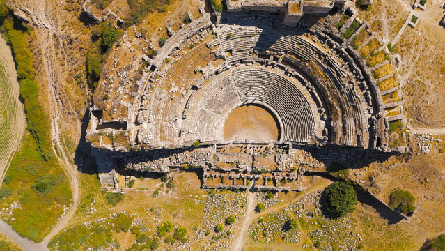 Balat, Turkey. Aerial drone view of the ancient Theatre of Miletus on its hill and the historic Ilyas Bey Caravanserai in front of it. Aerial View