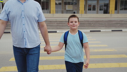 Fototapeta premium Family walks to school are the best, Child with a backpack ready for the day, Loving dad by his son’s side, Every school day is special, Boy’s smile before he learns, Growing up with daily walks