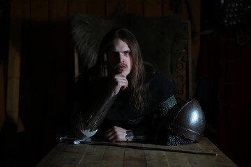 Obraz premium A mighty hero with long hair in chain mail armor in an ancient hall. Medieval warrior in the knight's chambers.