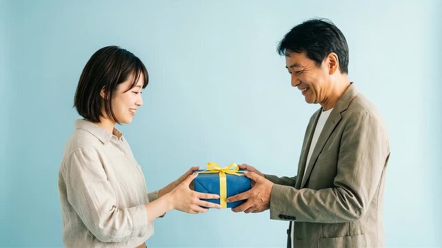 照れながらも父の日にプレゼントを渡す成人した娘と父親
