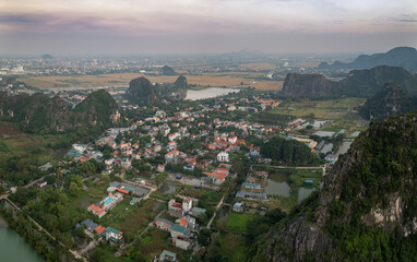 Obraz premium A scenic view of the mountains and city in Ninh Binh, Vietnam. The image captures the natural beauty of the landscape and the urban sprawl of the city in the background.