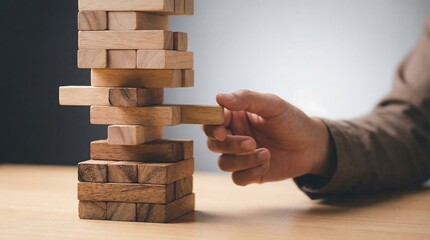 Hand carefully removing a wooden block from a precarious tower, symbolizing risk and strategy.