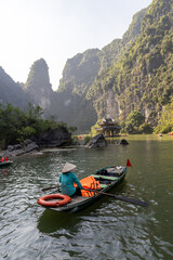 Tourists enjoy a boat tour of the Trang An river in Ninh Binh, Vietnam. The boats are rowed by local women, who take visitors to see the caves and limestone karsts.