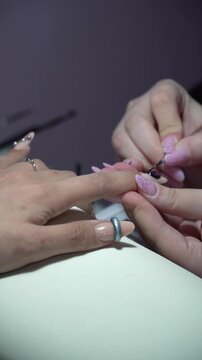 The process of nail extensions in a beauty salon. Nail coating with gel polish and top. Concept of spa body care for women.
Vertical shot