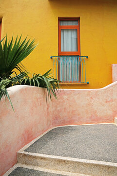 One window and yellow wall and stone steps . Stone house. European Mediterranean architecture