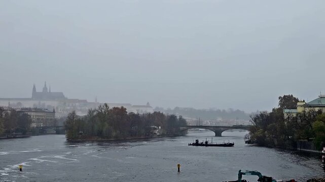 Panoramic view of St. Vitus Cathedral and Vltava River in Prague, Czech Republic in fog. The tram goes over the bridge.