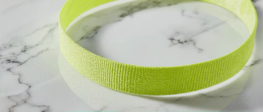 Neon Captain Band. Soccer/Football Merchandise Mockup (No Brand, No Logo). Merchandise Mockup. A neon yellow captain's armband laid flat and slightly curved, set on a polished white marble surface
