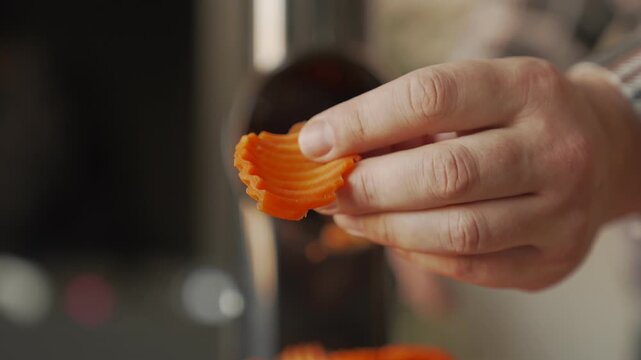 The hand holds a slice of carrot, showing the shape of the slice and the pattern