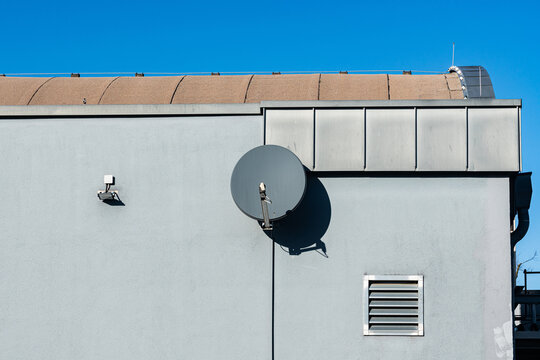Satellite dish on building wall under clear blue sky